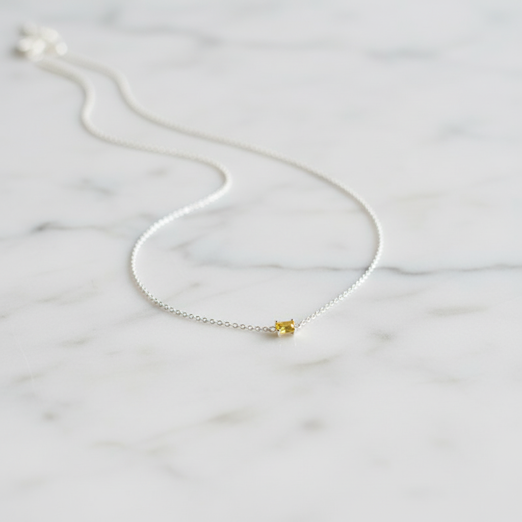 Silver chain necklace with yellow stone on marble